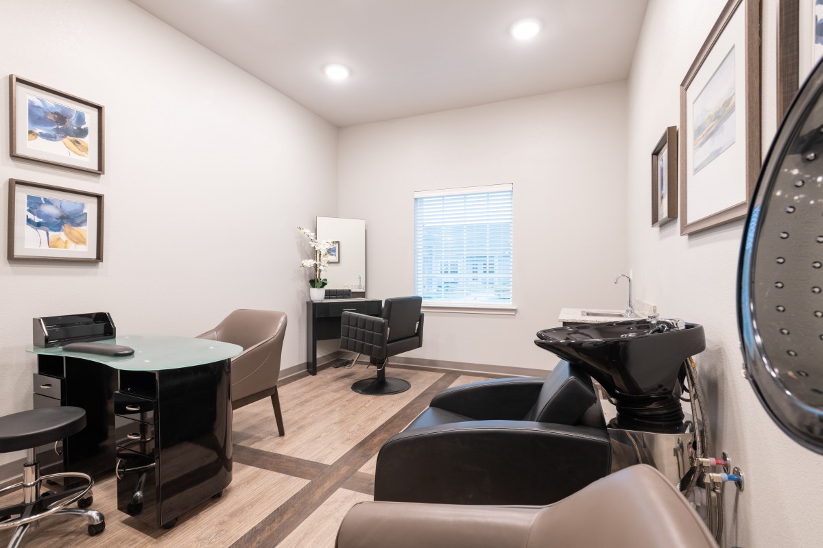 A modern hair salon interior with chairs, a sink, and ample lighting.