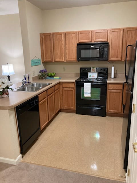 A modern kitchen with wooden cabinets and black appliances.