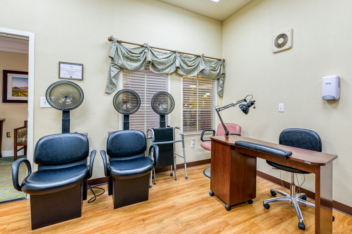 A salon interior with hair drying stations and a desk.