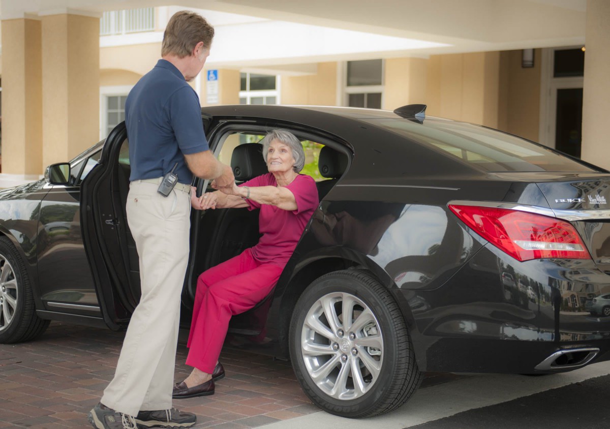 A person assisting an elderly woman as she gets out of a car.