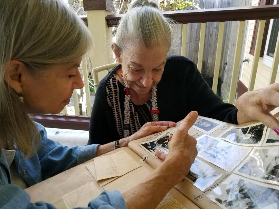 Two elderly women looking through a photo album together.