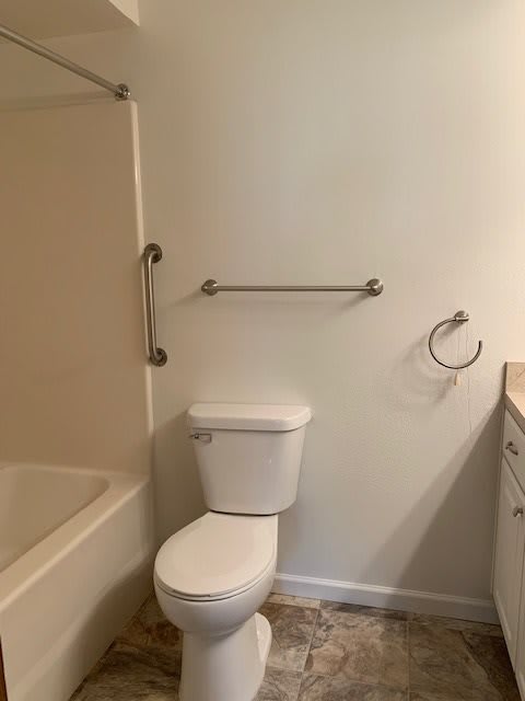 A bathroom with a toilet, bathtub, towel bar, and towel ring.