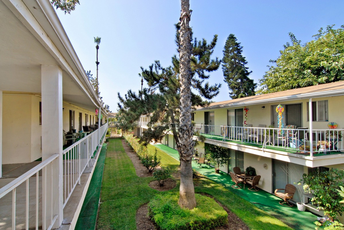 A view of a two-story apartment building with balconies overlooking a landscaped courtyard.