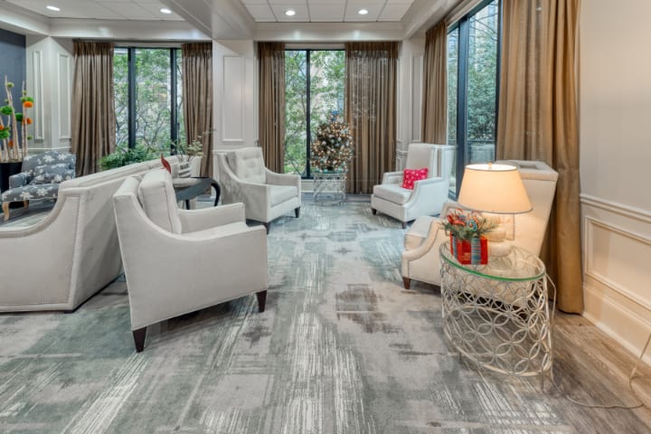 A modern living room with elegant furnishings, featuring armchairs, large windows, and soft lighting.