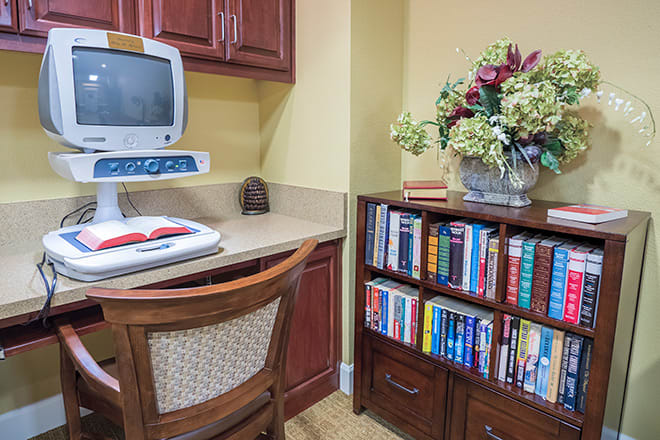 A cozy corner office setup with a computer, books, and decorative flowers.