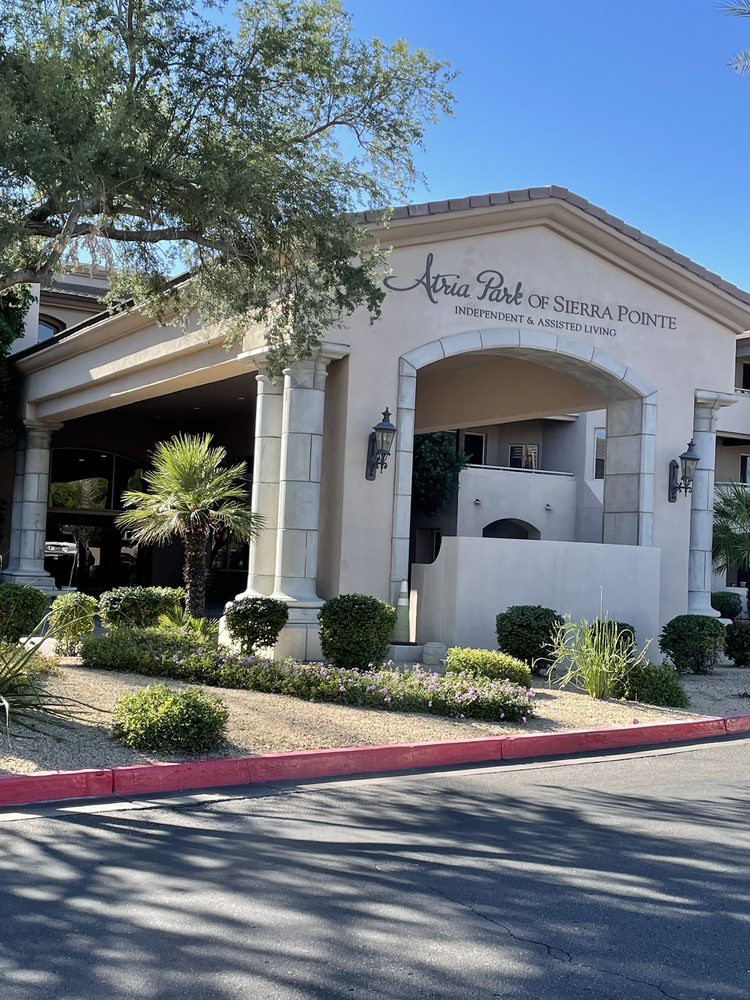 Front entrance of a building with landscaping and palm trees in a sunny setting.
