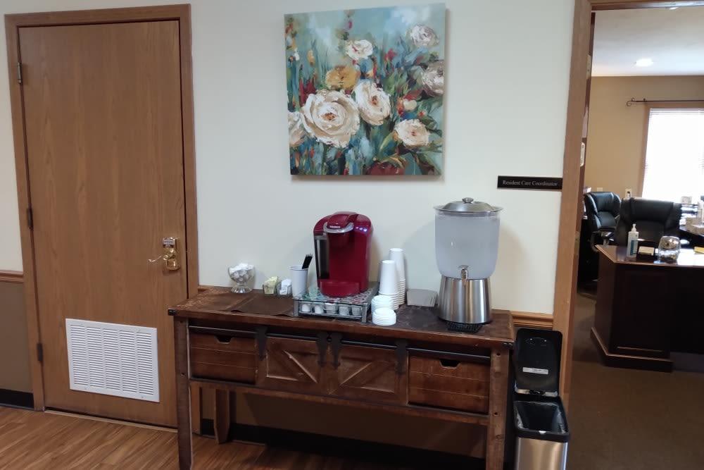 A cozy coffee station with a floral painting hanging above.