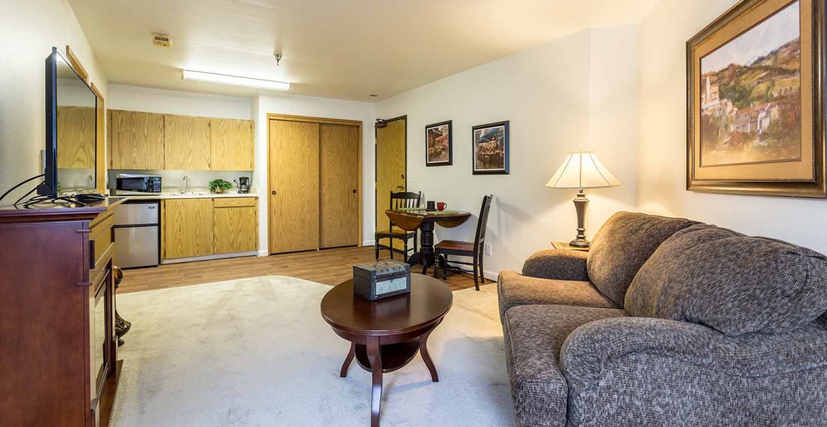 A cozy living room with a sofa, coffee table, and a small dining area.