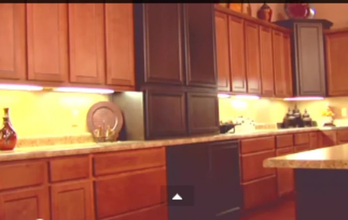 A kitchen with wooden cabinets and under-cabinet lighting.