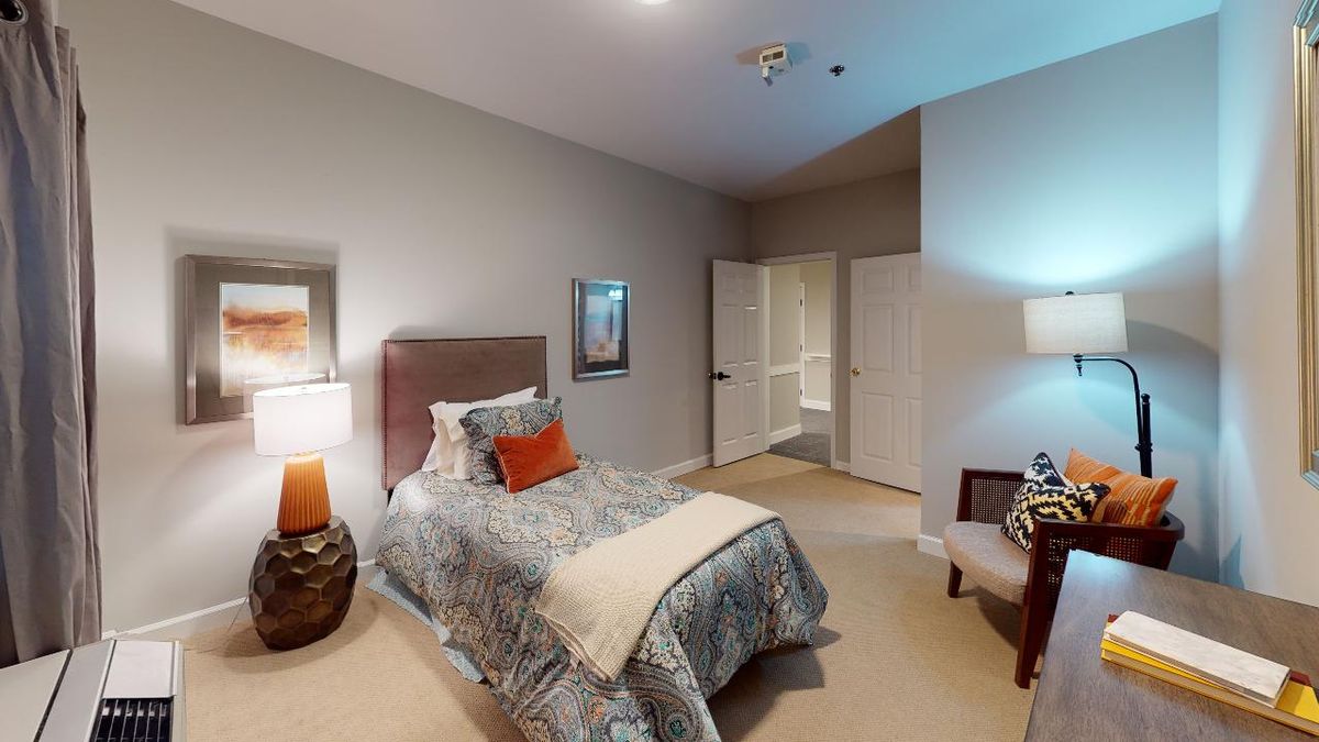 A cozy bedroom with a single bed, neutral decor, and soft lighting.