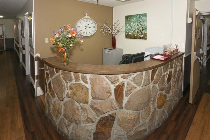A welcoming reception area featuring a stone wall, decorative flowers, and a large clock.
