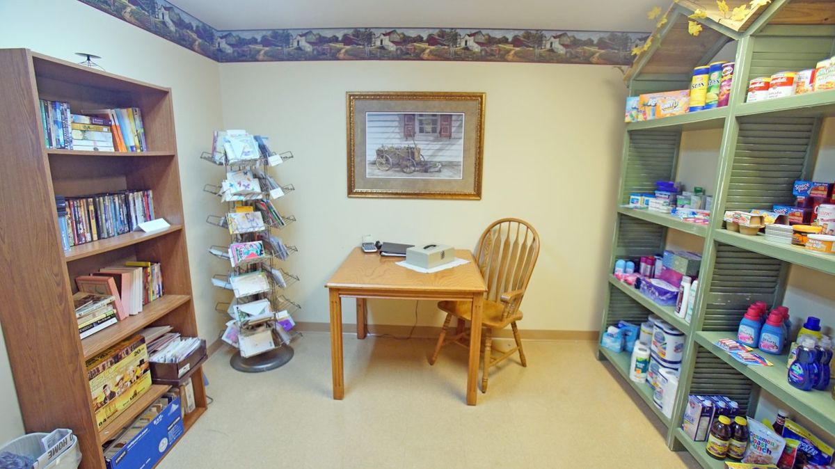 A small office with a wooden desk and chair, surrounded by shelves filled with books and supplies.