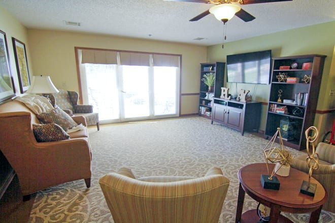 A cozy living room featuring a large window, comfortable seating, and a TV entertainment area.