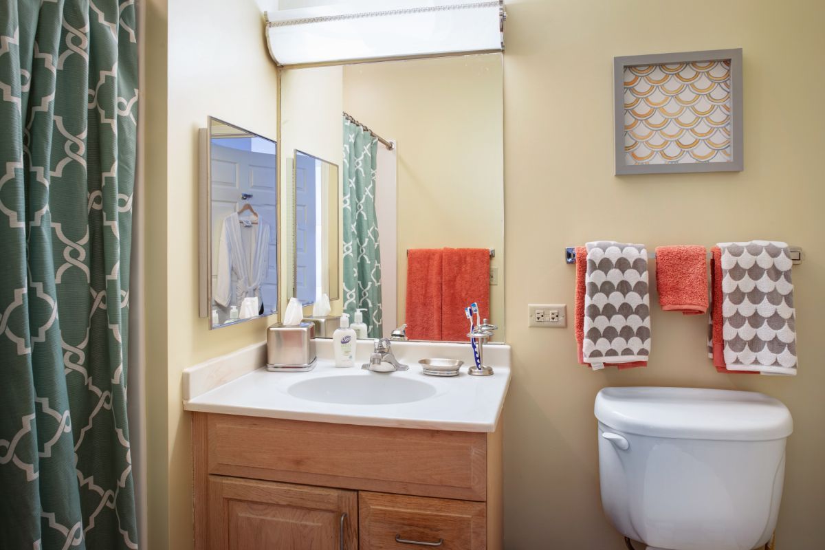 A neatly organized bathroom with a sink, mirror, and colorful towels.