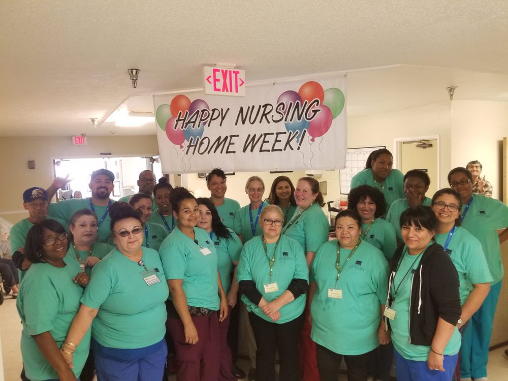 A group of staff members celebrating Nursing Home Week with a banner.