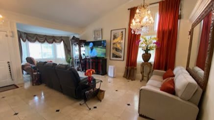 A cozy living room with a sofa, television, and elegant chandelier.