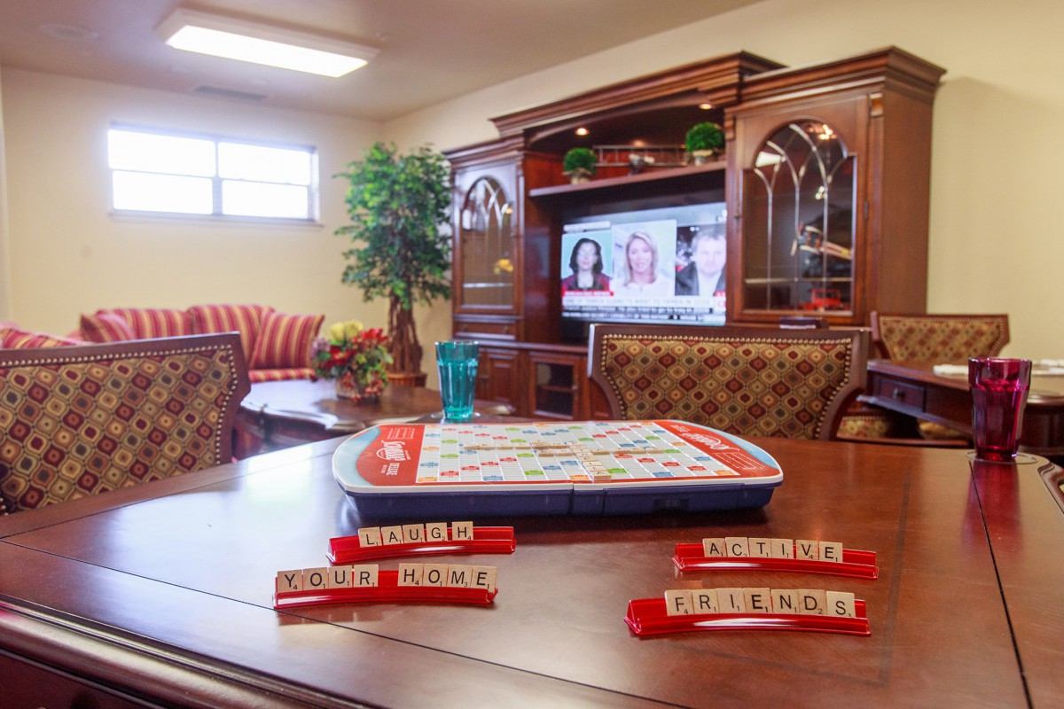 A cozy living room with a Scrabble game set up on the table and a TV in the background.