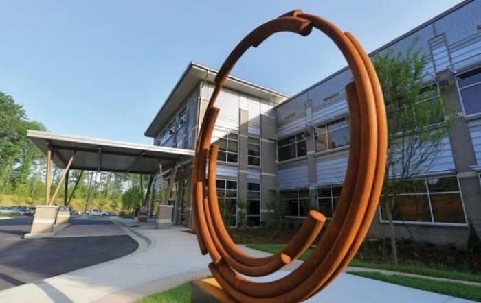 A modern metal sculpture in front of a contemporary building.