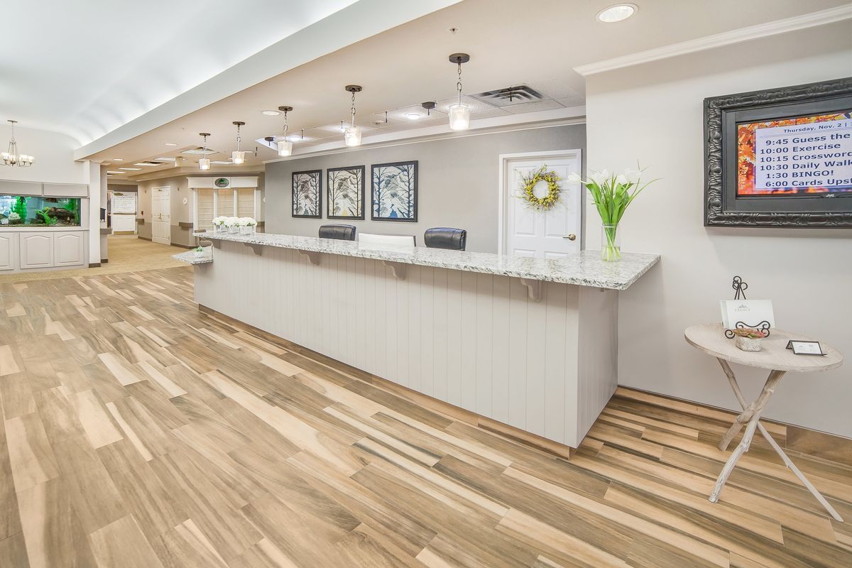 A modern reception area with a long desk, wood flooring, and elegant decor.