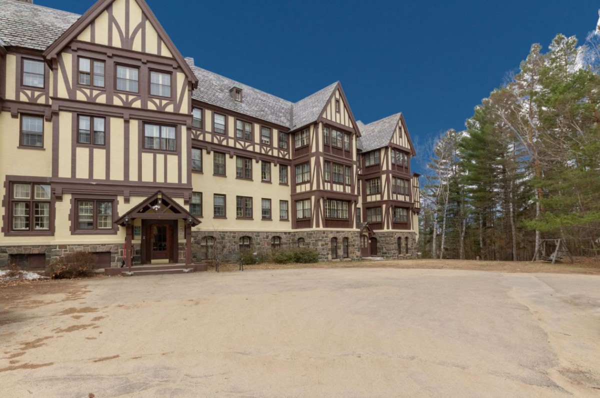A historic Tudor-style building surrounded by trees on a clear day.