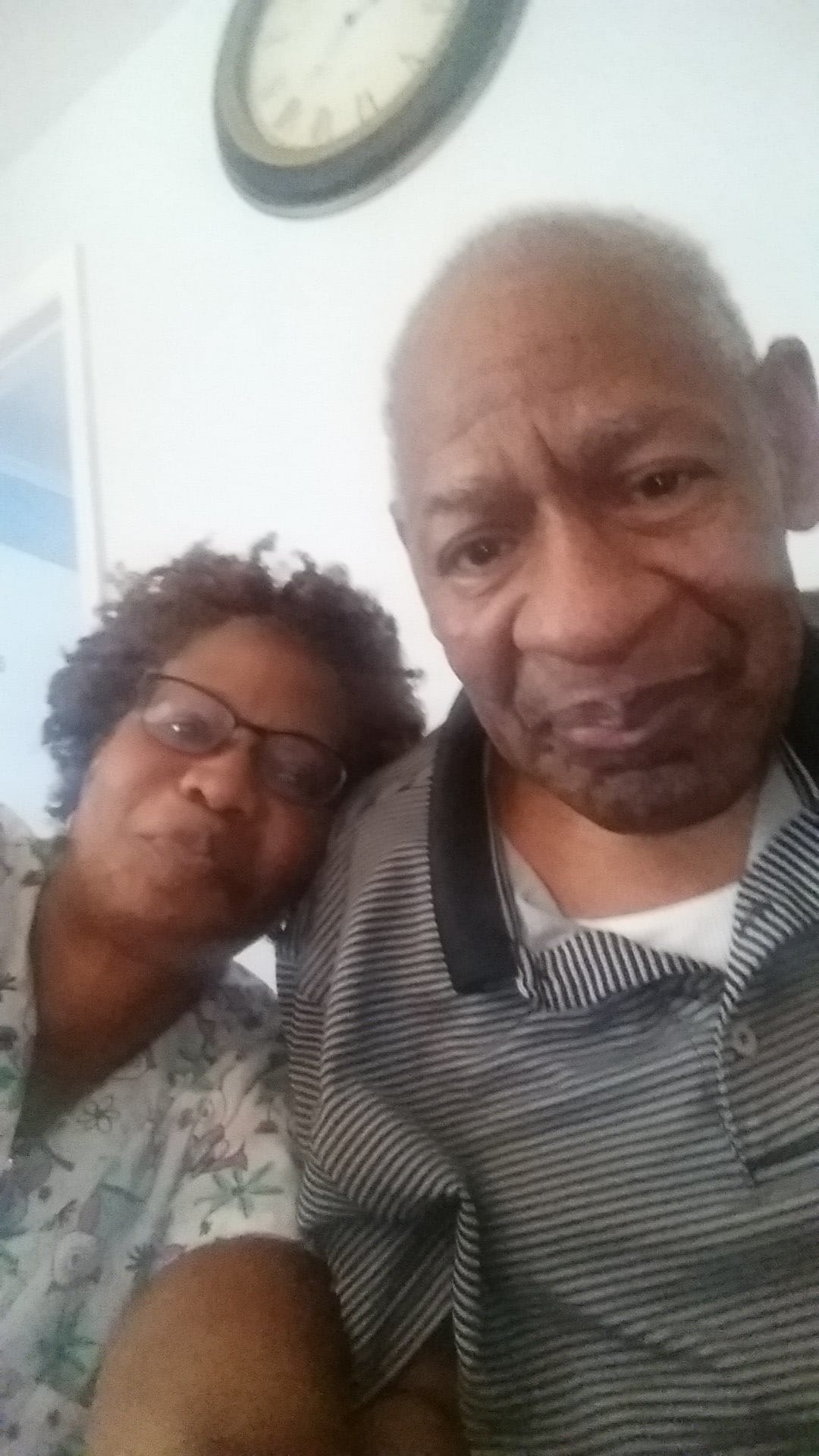 An elderly couple taking a selfie indoors.