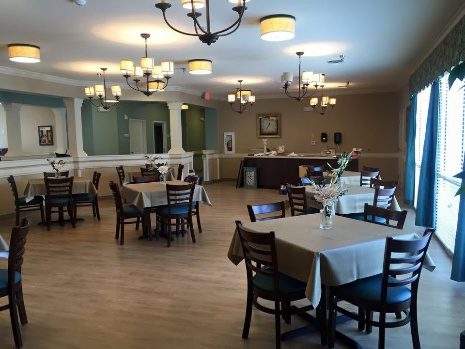 A cozy restaurant dining area with neatly arranged tables and chairs, illuminated by chandeliers.