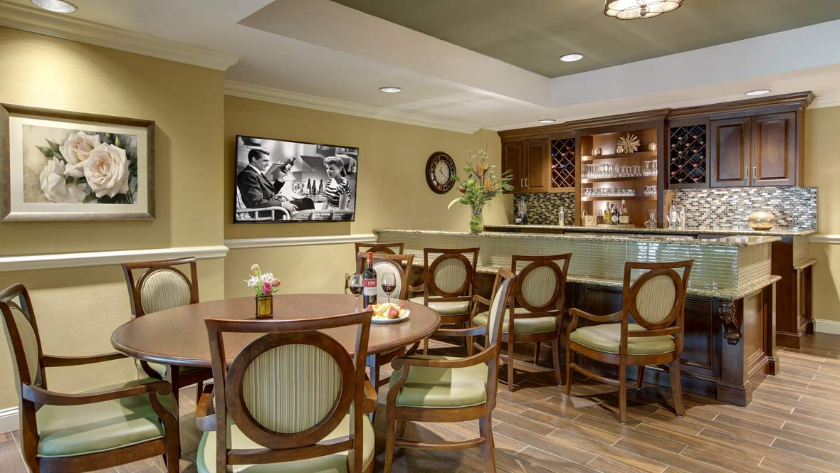 A cozy dining area with elegant seating and a small bar, featuring a television on the wall.
