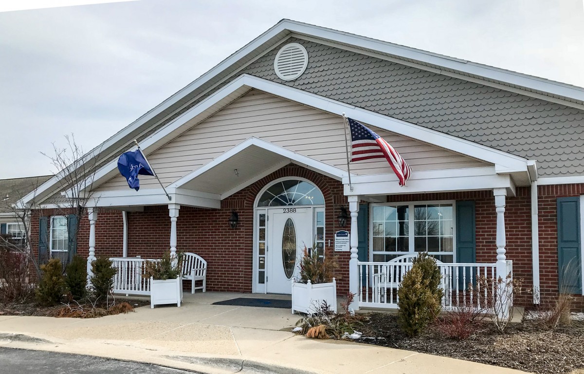 A building with a front entrance displaying two flags on poles.