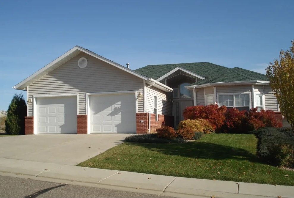 A suburban house with a two-car garage and a well-maintained lawn.