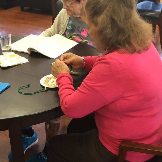 Two individuals enjoying a relaxing moment, one knitting and the other reading at a cafe table.