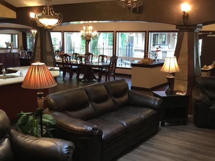 A cozy living and dining space featuring a leather sofa, warm lighting, and a wooden dining set.