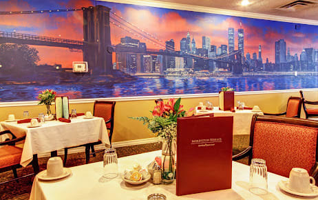 A cozy restaurant setting with elegantly set tables and a vibrant cityscape mural on the wall.