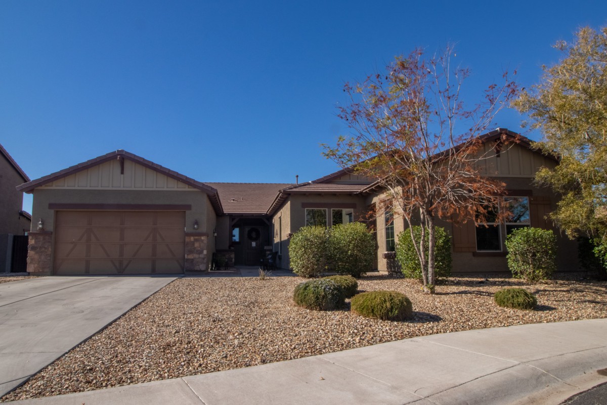 A suburban house with a landscaped front yard and driveway on a clear day.