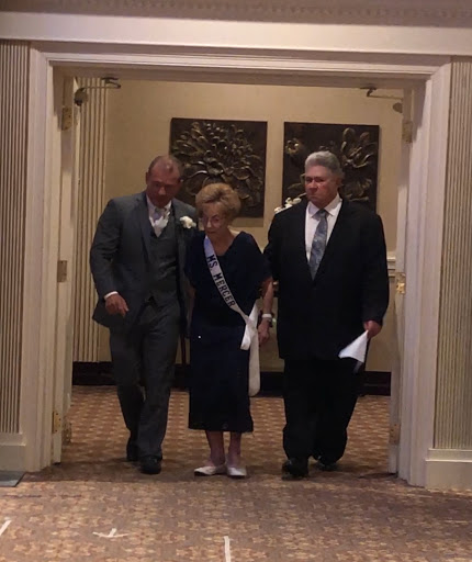 A couple walks hand-in-hand with a guest during a formal event.