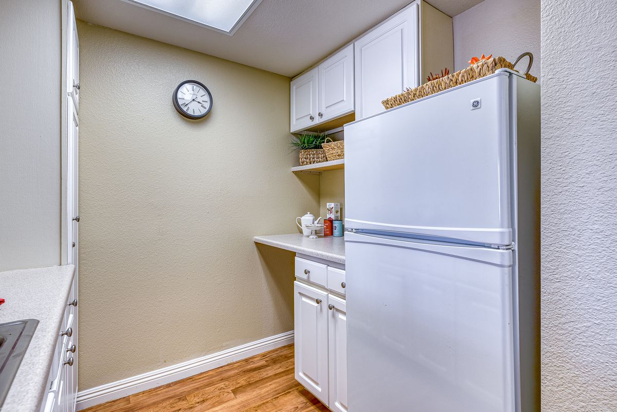 A clean and organized kitchen space with a white refrigerator, cabinets, and shelves.