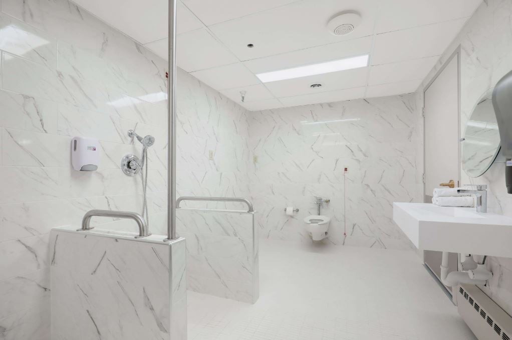 Modern accessible bathroom with white marble walls and safety features.