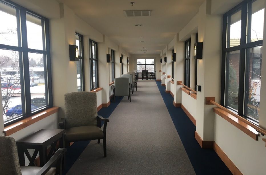 A long, well-lit hallway with chairs and windows lining the sides.