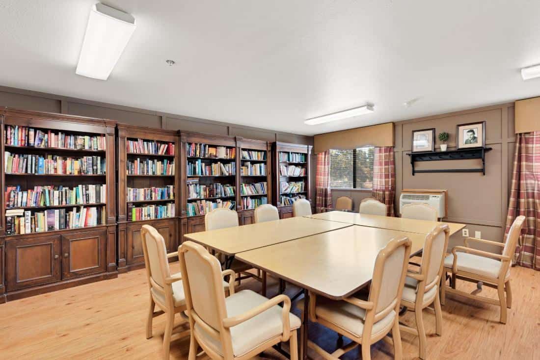 A quiet meeting room with a large conference table surrounded by bookshelves filled with books.
