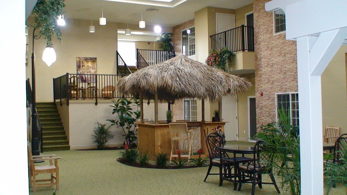 Indoor seating area with a tiki hut bar and surrounding plants.