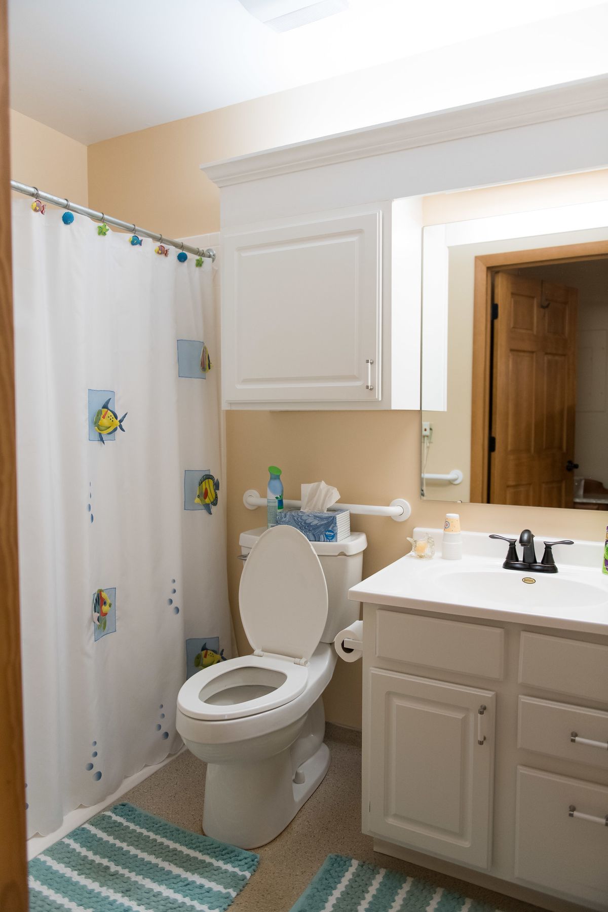 A clean and organized bathroom with a shower curtain and white cabinetry.
