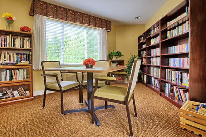 Cozy reading room with bookshelves and a table by the window.