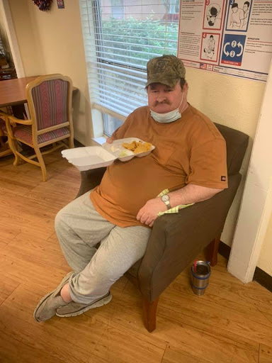 A man sitting comfortably in a chair, enjoying his meal.