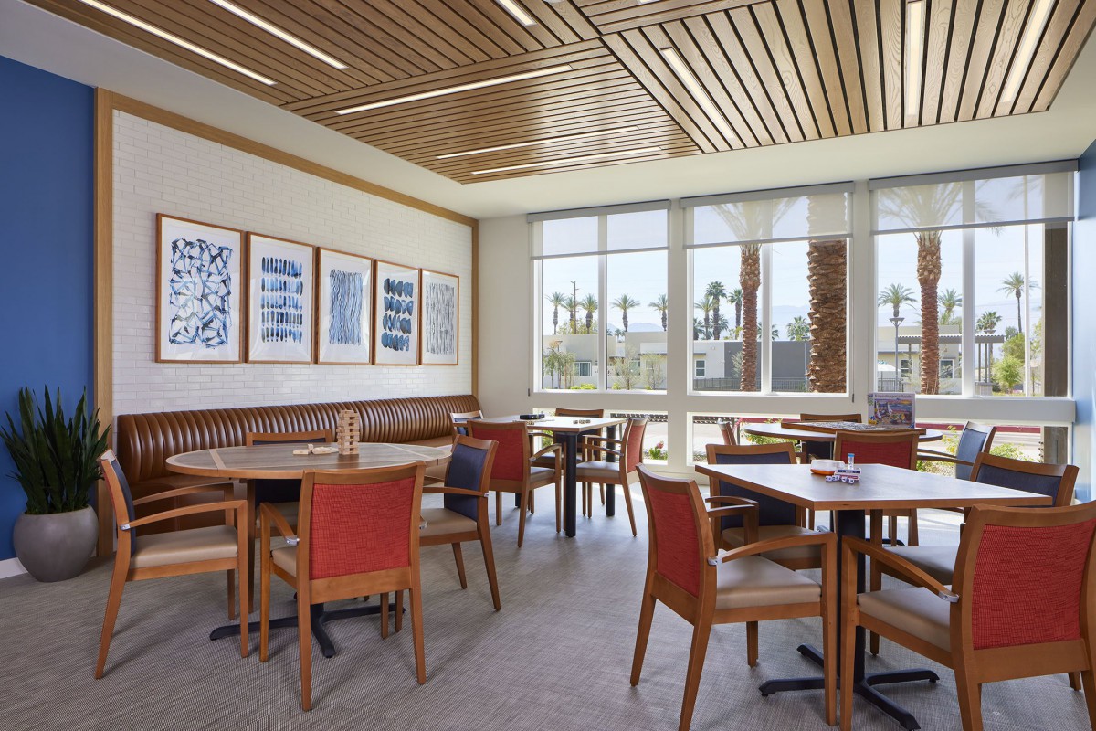 A modern restaurant dining area with wooden furnishings and large windows.