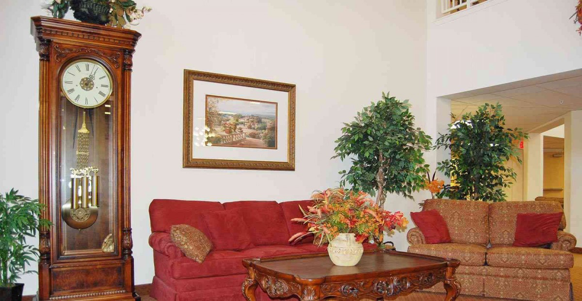 A cozy living room with a red sofa, framed artwork, and decorative plants.