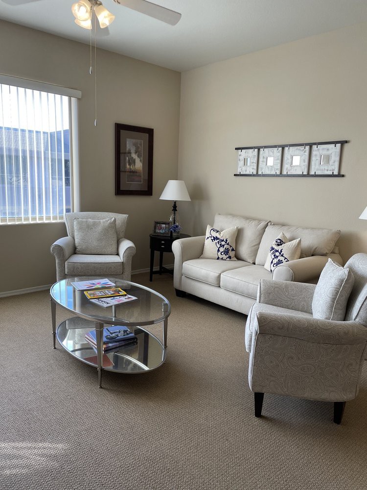 A cozy living room with a comfortable sofa, two armchairs, and a glass coffee table, all arranged around decorative elements.