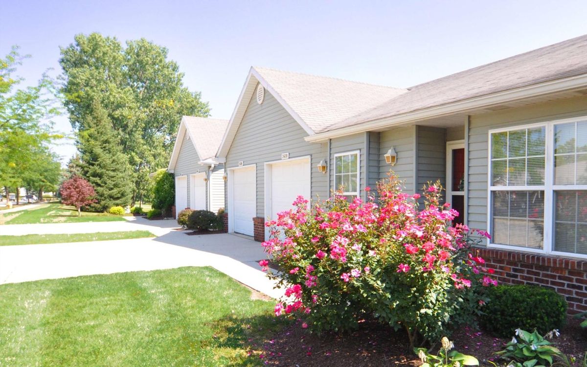 A row of suburban houses with a neatly landscaped garden and driveway.