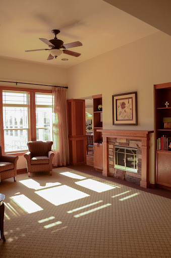 A cozy living room with warm wood tones and soft sunlight streaming through the large windows.
