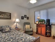 Cozy bedroom with patterned bedding, a comfy chair, and warm lighting.