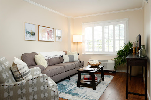 A cozy living room featuring a comfortable couch, artistic wall decor, and natural light from the windows.
