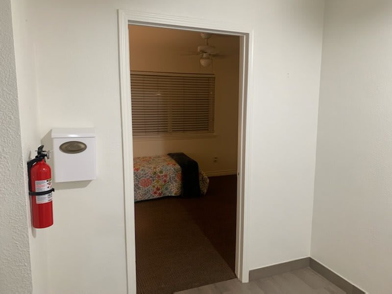 A view through a doorway into a bedroom with a bed and window.